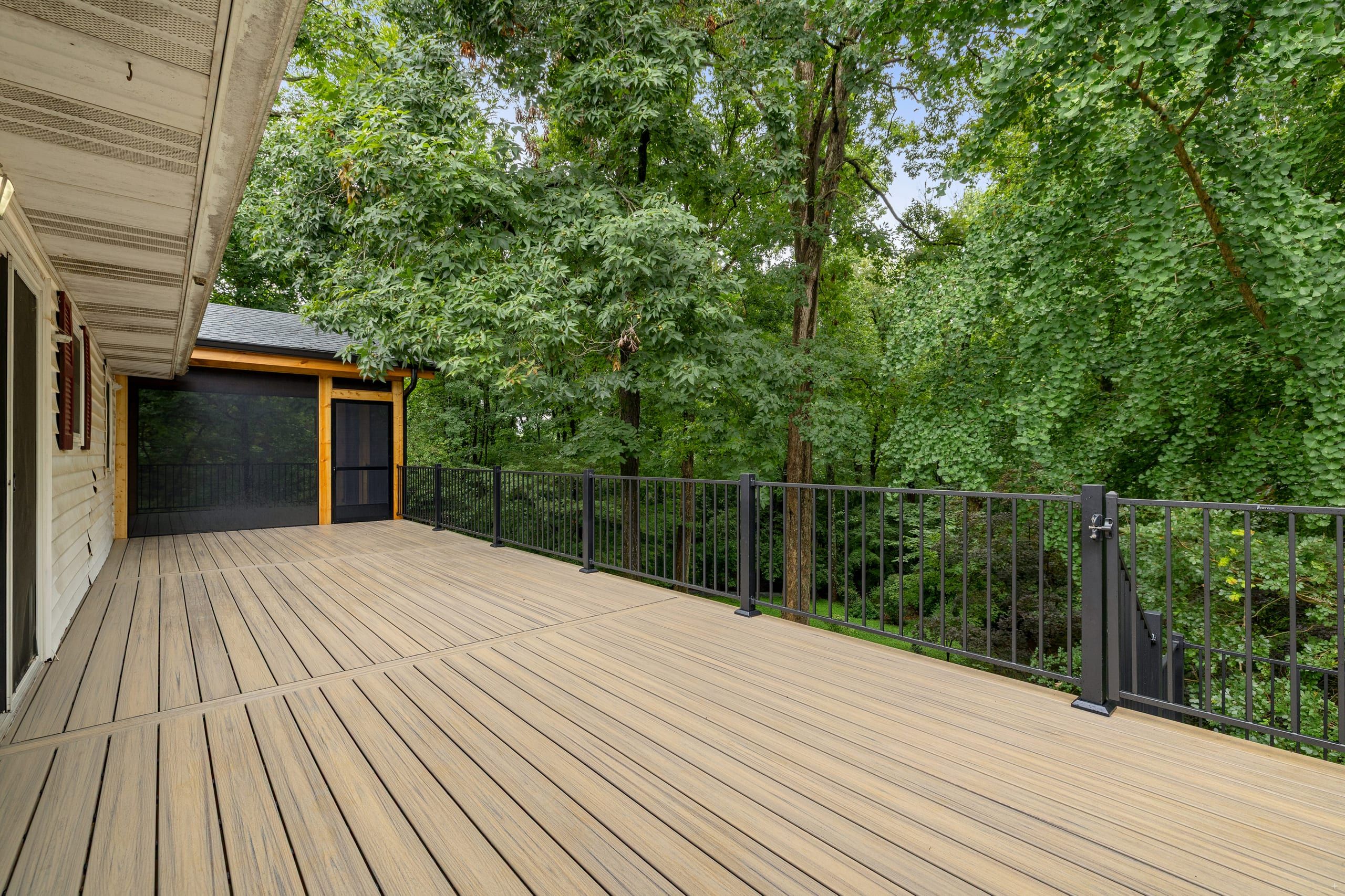 Venice composite deck looking toward the screened porch enclosure with a black aluminum railing and self-closing gate