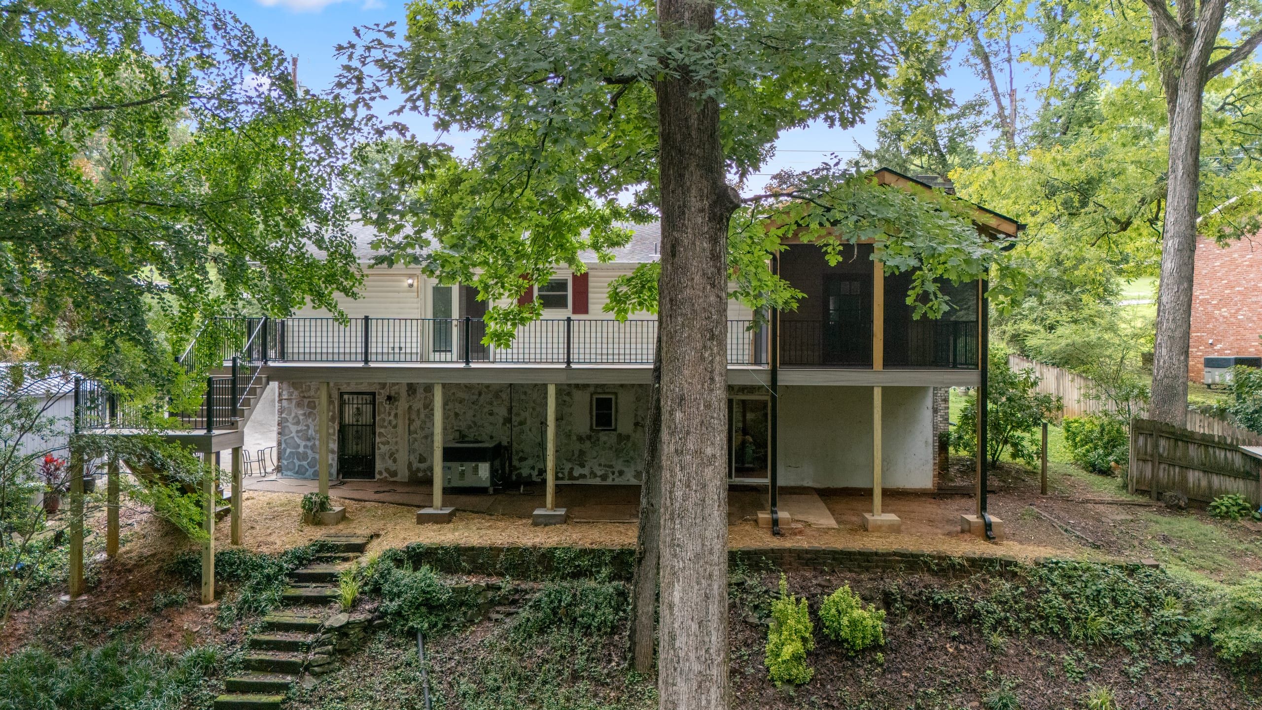 Full rear elevation of the Venice raised home with the elevated deck and screened porch above a stone walk-out level