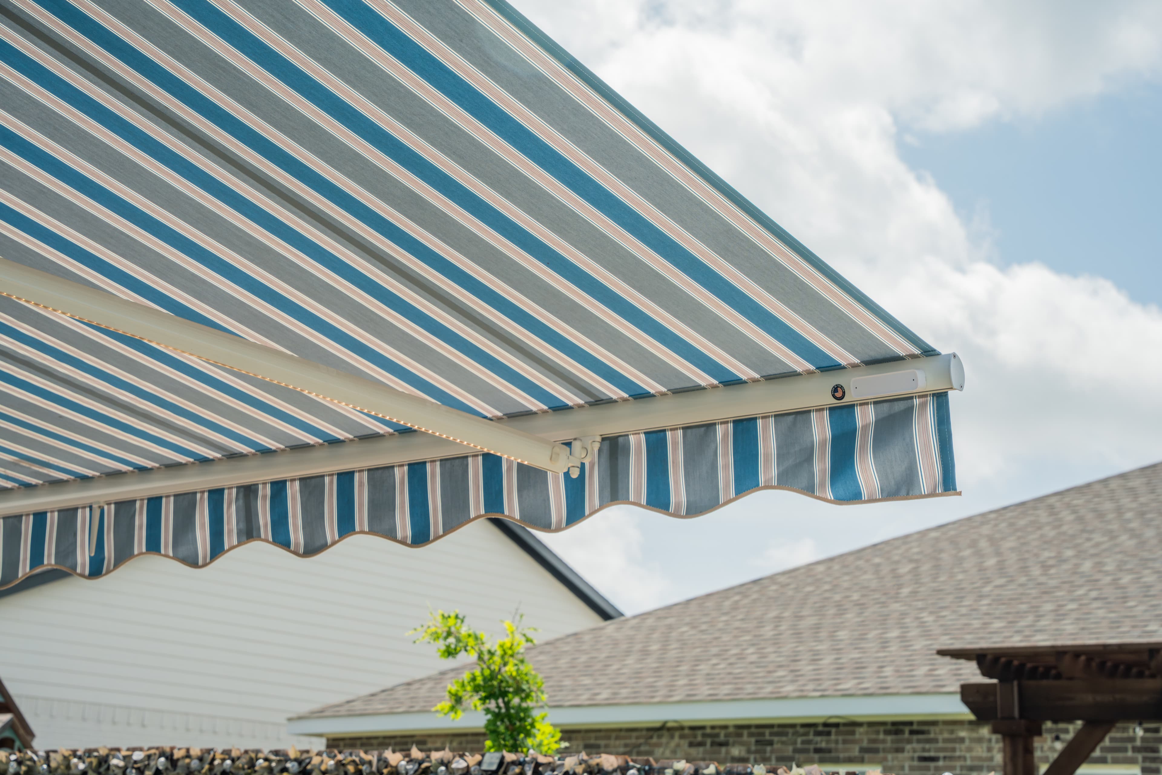 Wind sensor mounted on the front bar of a blue-striped SunPro retractable awning